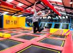 Persona saltando en una zona de trampolines dentro del parque