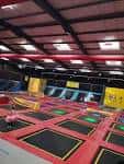 Área de trampolines con colchonetas rojas y estructuras de juego