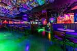 Interior del bar con iluminación de neón y ambiente festivo