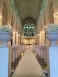 Vista del pasillo central de la iglesia decorado para una boda con alfombra blanca y arreglos florales