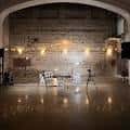 Interior del auditorio con escenario iluminado, suelo pulido y arcos decorativos