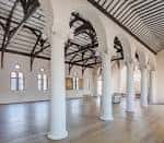 Salón amplio con columnas blancas y suelo de madera pulida