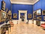 Sala de exposiciones con paredes azules y mobiliario clásico
