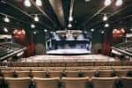 Interior del auditorio con butacas y escenario vacío