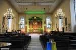 Interior de la iglesia con bancos, candelabros y altar iluminado