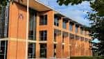 Edificio moderno de ladrillo rojo con grandes ventanales en el campus
