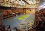 Interior del pabellón con cancha deportiva y gradas vacías