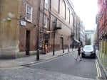Vista de la calle Archer Street con edificios históricos y un coche estacionado