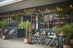 Fachada del bar Archer Street con mesas exteriores y plantas decorativas