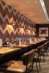 Barra larga con asientos y pared decorada con patrón geométrico