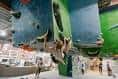 Vista general del gimnasio de escalada con múltiples rutas y escaladores