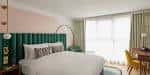 Habitación estándar con cama doble, cabecero verde y cortinas claras