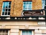 Señal de dirección al Museo Charles Dickens en fachada de ladrillo