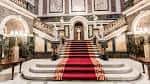 Gran escalinata interior con alfombra roja y columnas decorativas