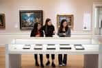 Interior de una galería con obras expuestas y visitantes observando