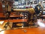 Primer plano de una máquina de coser industrial antigua dorada sobre mesa de madera