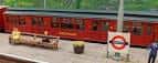 Detalle de un vagón rojo en una estación de ferrocarril en miniatura con señalización británica