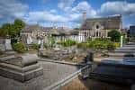 Panorámica del cementerio con tumbas, senderos y edificios históricos bajo cielo azul