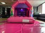 Interior del local con un castillo inflable rosa montado para eventos