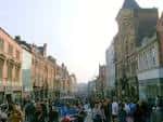 Vista diurna de Briggate con edificios históricos y peatones caminando