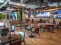 Área de comedor con mesas modernas y decoración industrial