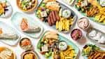 Composición de diversos platos de comida mediterránea dispuestos sobre una mesa blanca