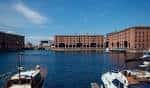 Vista panorámica del Royal Albert Dock con edificios de ladrillo rojo y embarcaciones en el canal