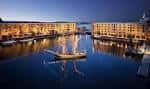 Royal Albert Dock iluminado al atardecer con reflejos en el agua y una embarcación en el centro