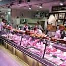 Interior del mercado mostrando puestos de carnicería y clientes comprando
