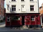 Entrada principal del pub The Red Deer con puertas y ventanas de color rojo oscuro