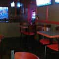 Interior del bar con mesas altas y sillas rojas