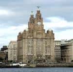 Vista frontal del Royal Liver Building con sus torres icónicas y el río Mersey al fondo