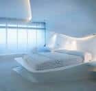 Detalle de la cama en una suite con diseño orgánico y luz indirecta