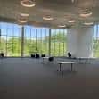 Interior espacioso de la biblioteca con grandes ventanales y mesas dispuestas para eventos