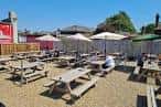 Terraza exterior de Redwell Brewery con mesas de picnic y sombrillas