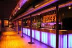 Interior del bar con iluminación de neón y barra iluminada