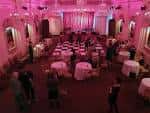 Interior del salón de Bush Hall decorado para una recepción con mesas redondas y luces rosas