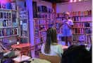 Interior del local durante un evento con público y estanterías de libros al fondo