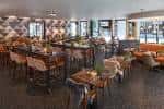 Interior del restaurante con mesas altas, sillas modernas y decoración geométrica en la pared
