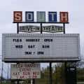 Letrero principal del South Drive-In Theatre mostrando horarios de mercado de pulgas