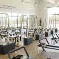 Vista general del espacio de entrenamiento con equipos de pilates y grandes ventanales