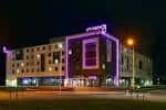Fachada del hotel Moxy Edinburgh iluminada por la noche con luces de neón
