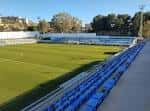 Detalle de las gradas laterales del estadio con asientos azules bajo el sol