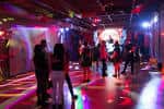 Interior del local con iluminación de discoteca y personas bailando