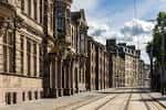 Constitution Street con arquitectura clásica y vías de tranvía bajo cielo parcialmente nublado