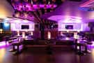 Vista interior del espacio Coco Boho con iluminación púrpura y mesas dispuestas para eventos