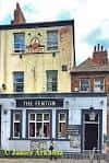 Vista exterior del pub The Fenton en Leeds con su fachada amarilla y letrero