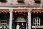 Pareja frente a la entrada decorada de Saint Paul's House durante una boda