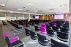 Sala de conferencias interior con butacas negras y moradas dispuestas en filas