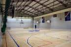 Vista interior de la cancha de baloncesto con suelo de madera y canastas